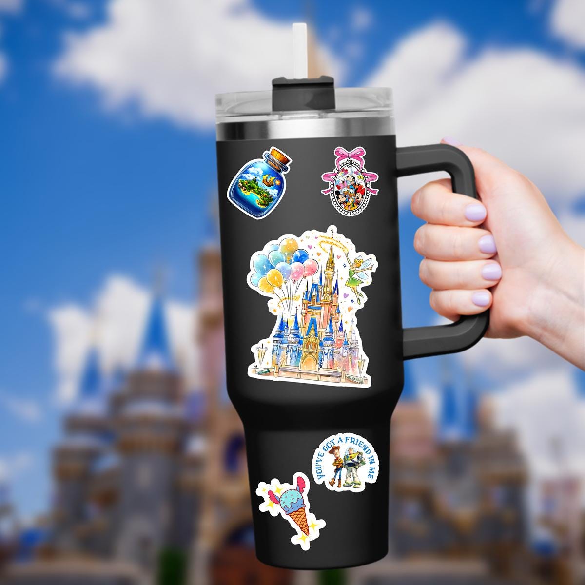 Disney World Castle Balloons TinkerBelle Laptop Sticker/ Magic Kingdom Fantasyland Disney decal/ planner water bottle cell phone decal A colorful Disney castle sticker held in a hand. The castle is painted with shades of blue, pink, and gold, featuring multiple turrets and a detailed facade. A fairy with green attire and wings hovers nearby, waving a wand. A cluster of balloons in yellow, blue, and pink floats above the castle.