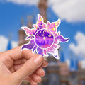 Rapunzel Tangled Lantern Sticker: Waterproof Vinyl Decal HydroFlask. A purple sun-shaped sticker featuring a scene from the movie Tangled. The sun has a white outline with a purple and pink gradient. Inside the sun is a silhouette of a boat with two people and a castle in the background. The sun's rays are filled with yellow lanterns.