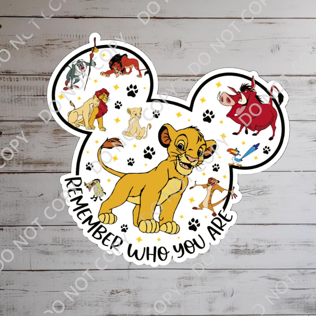 A colorful Lion King themed sticker in the shape of Mickey Mouse ears. The sticker features Simba, Timon, Pumbaa, and other characters. The phrase 'Remember Who You Are' is written in a curved font. Paw prints and stars are scattered around the characters.