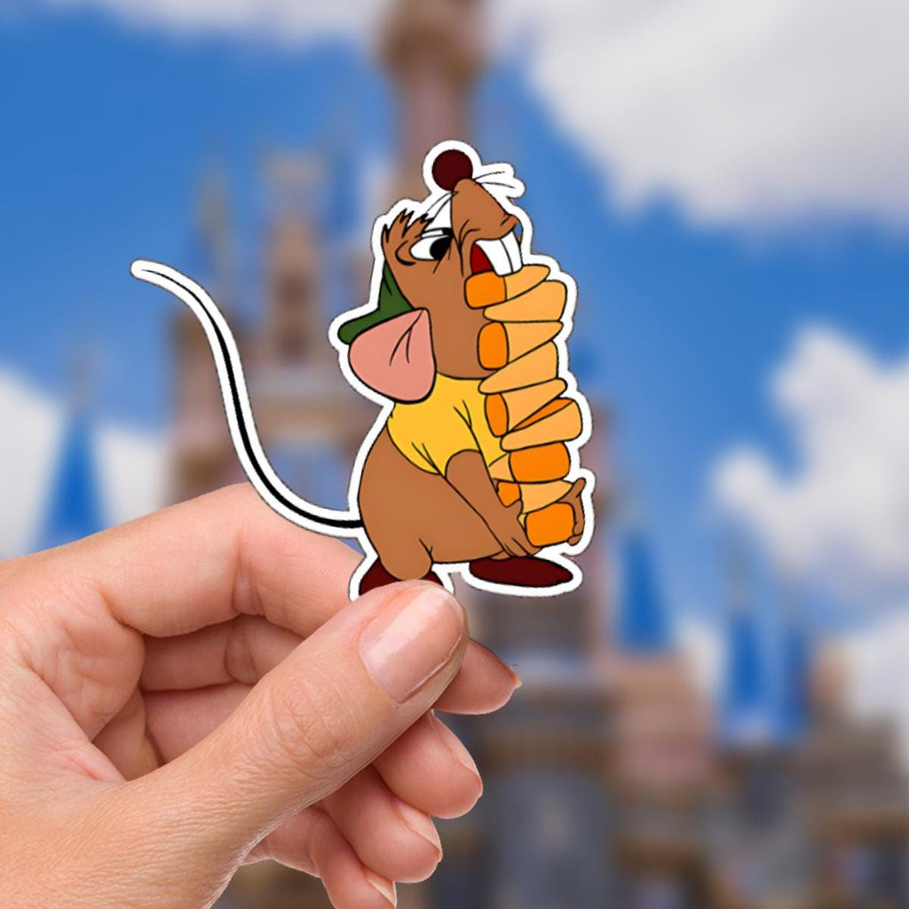 Cinderella Gus Gus Glass SlipperDisney Castle Decal Laptop Sticker/ Walt Disney decal cell phone MickeyMouse planner stationery water bottle. a sticker featuring a cartoon mouse character from Cinderella. The mouse is brown with a yellow shirt and a green hat. It is holding a stack of orange pancakes. The background is a blurred image of a blue sky and a castle.