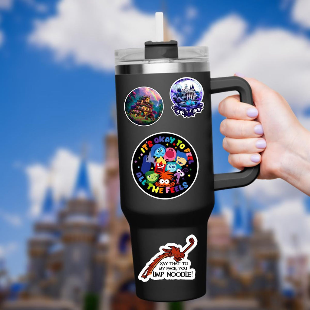 Inside Out Sadness Sticker: Waterproof Vinyl Decal Hydro Flask  Black tumbler with a handle and a straw. The tumbler has multiple stickers, including one with the text 'It's okay to feel all the feels,' and another with the text 'Say that to my face, you limp noodle!' The background is a blurred image of a castle.