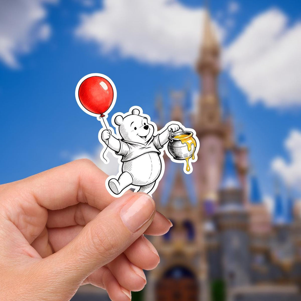 Disneyy  Winnie The Pooh Disney Laptop Sticker Positive Affirmation planner stationery decal water bottle cell.  : A sticker featuring Winnie the Pooh holding a red balloon. The bear is white with a red shirt and black outline. The balloon is a solid red circle. The background is blurred, showing a castle and blue sky with clouds. The sticker is held by a hand.